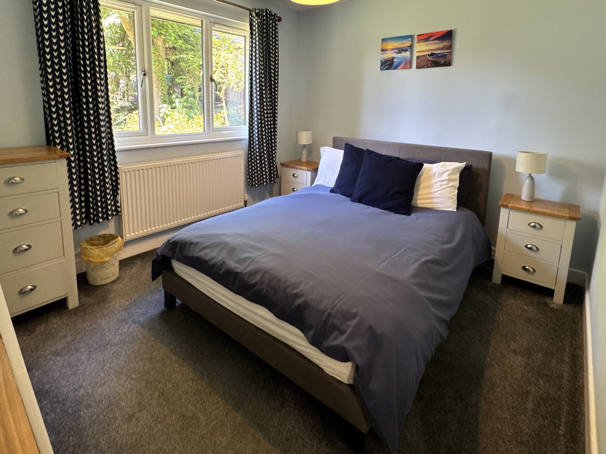 The double bedroom at Bencoolen, the bed made up in navy and white with a chest of drawers and bedside tables either side