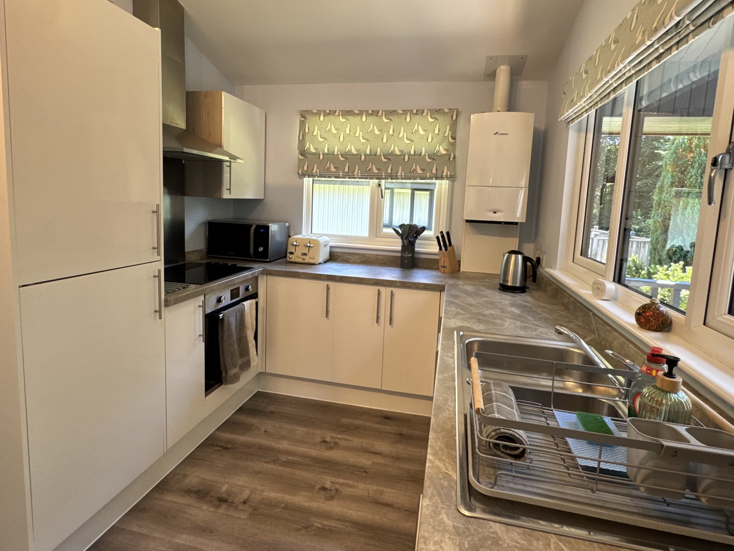 The kitchen at Bencoolen, with an oven and hob, a fridge-freezer, a kettle and toaster on the worktop and a sink beneath a large window