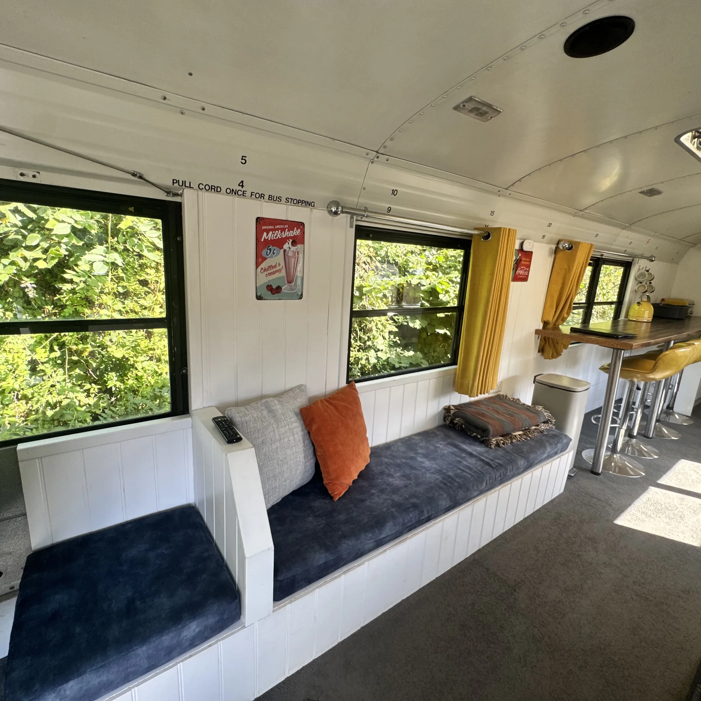 Cushioned bench seating along the bus windows, with scatter cushions and a throw