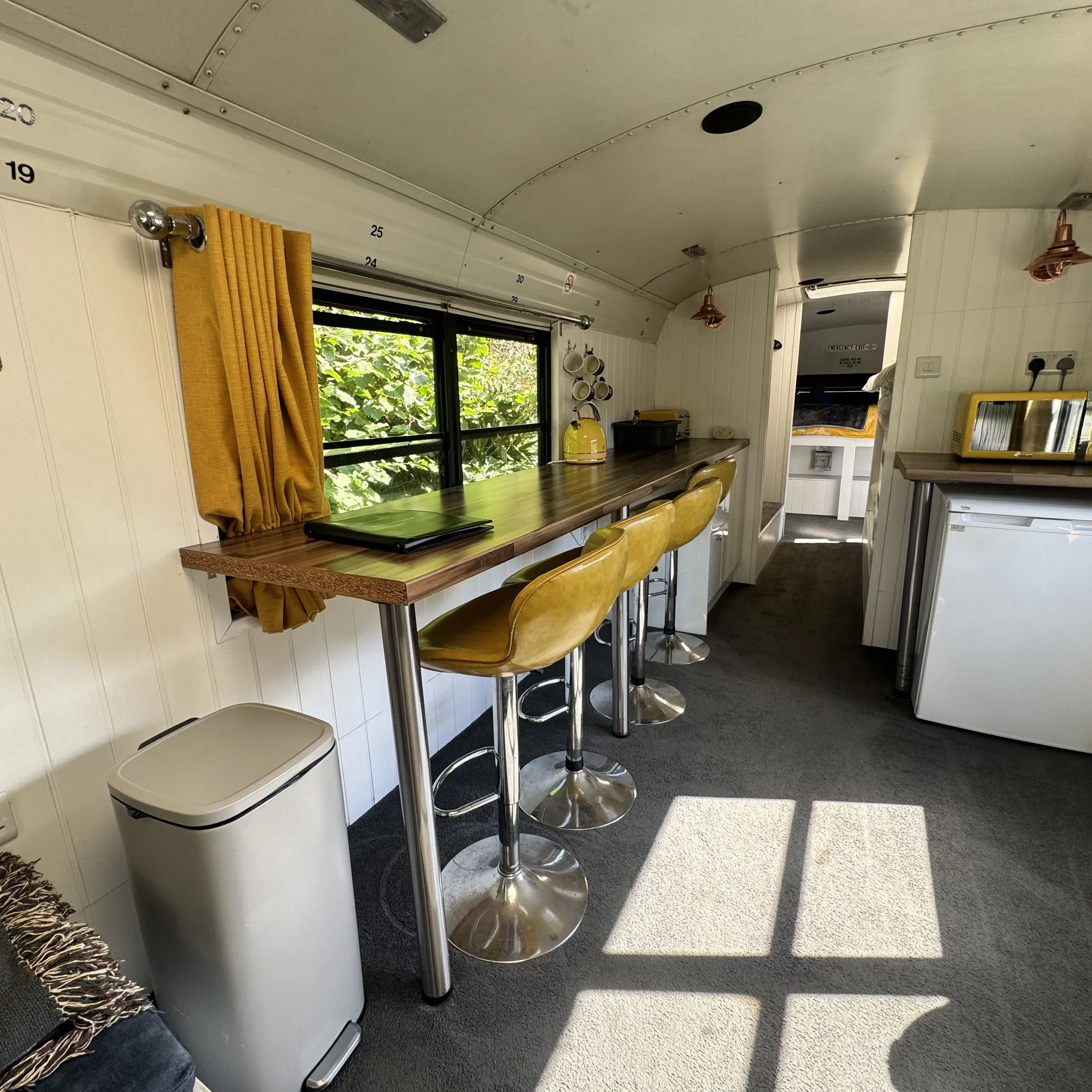 Yellow bar stools at the timber breakfast bar, with the kettle and mugs on the counter