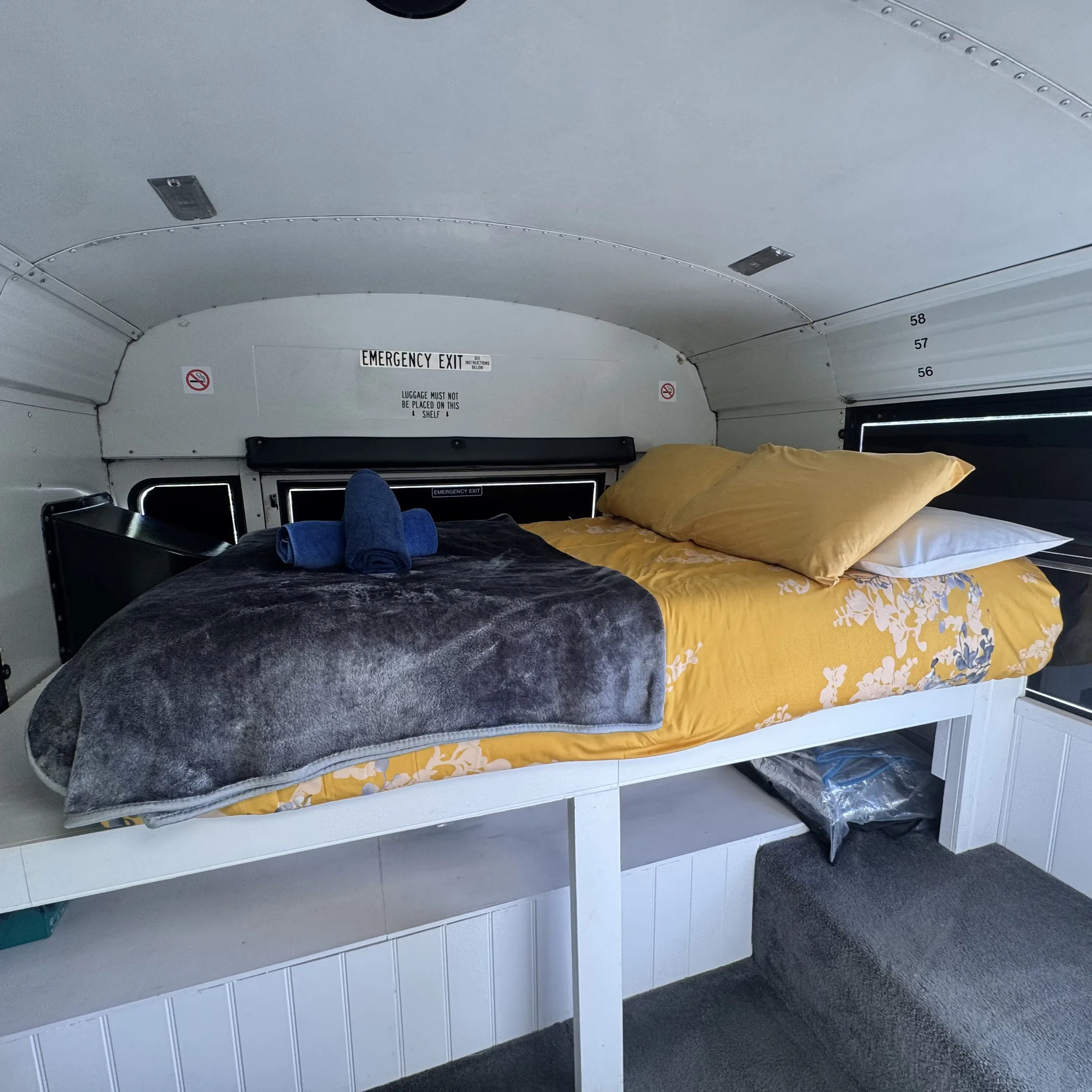 The made-up double bed at the back of the bus, under the original row of windows