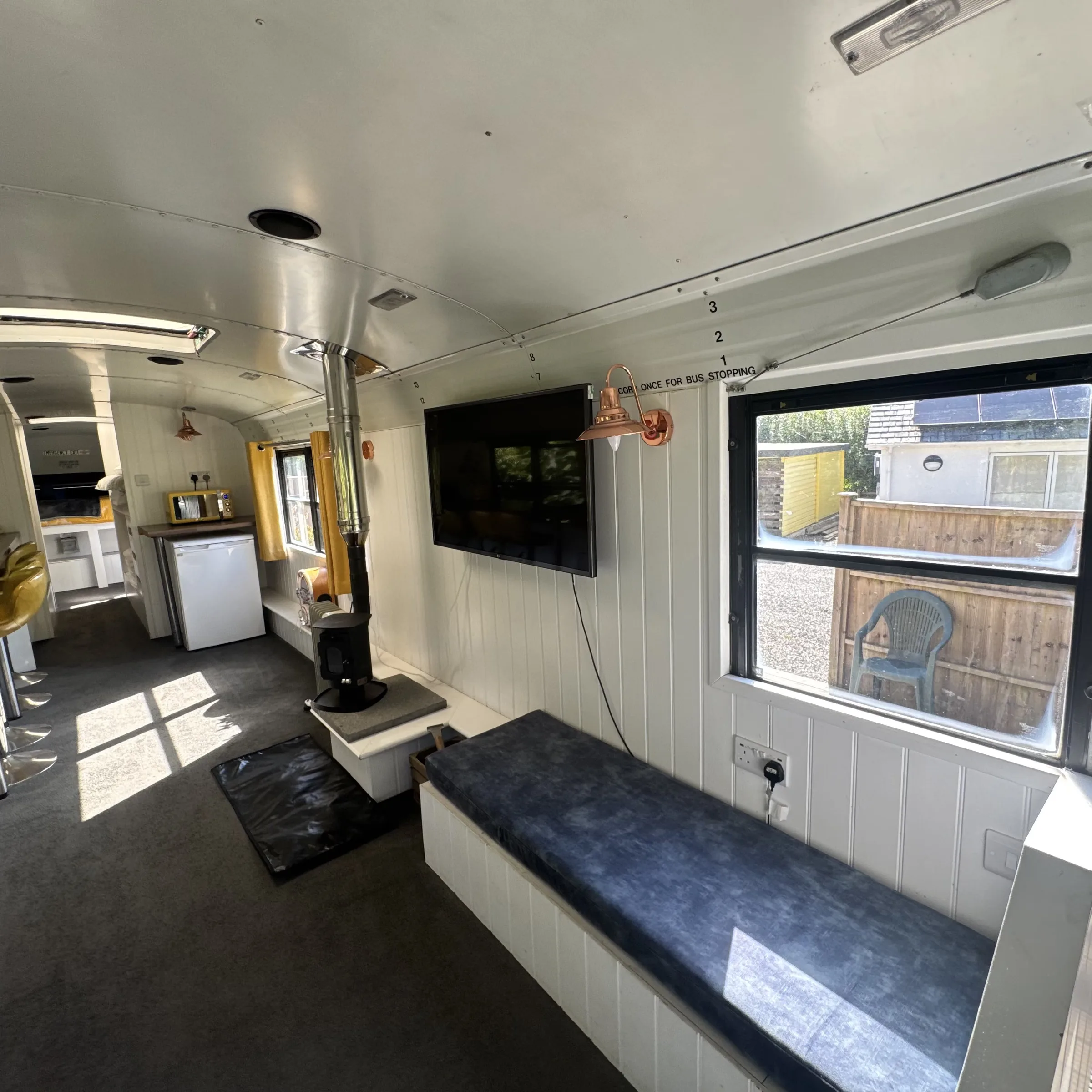 The log burner and TV in the living area, with the flue running up through the bus roof