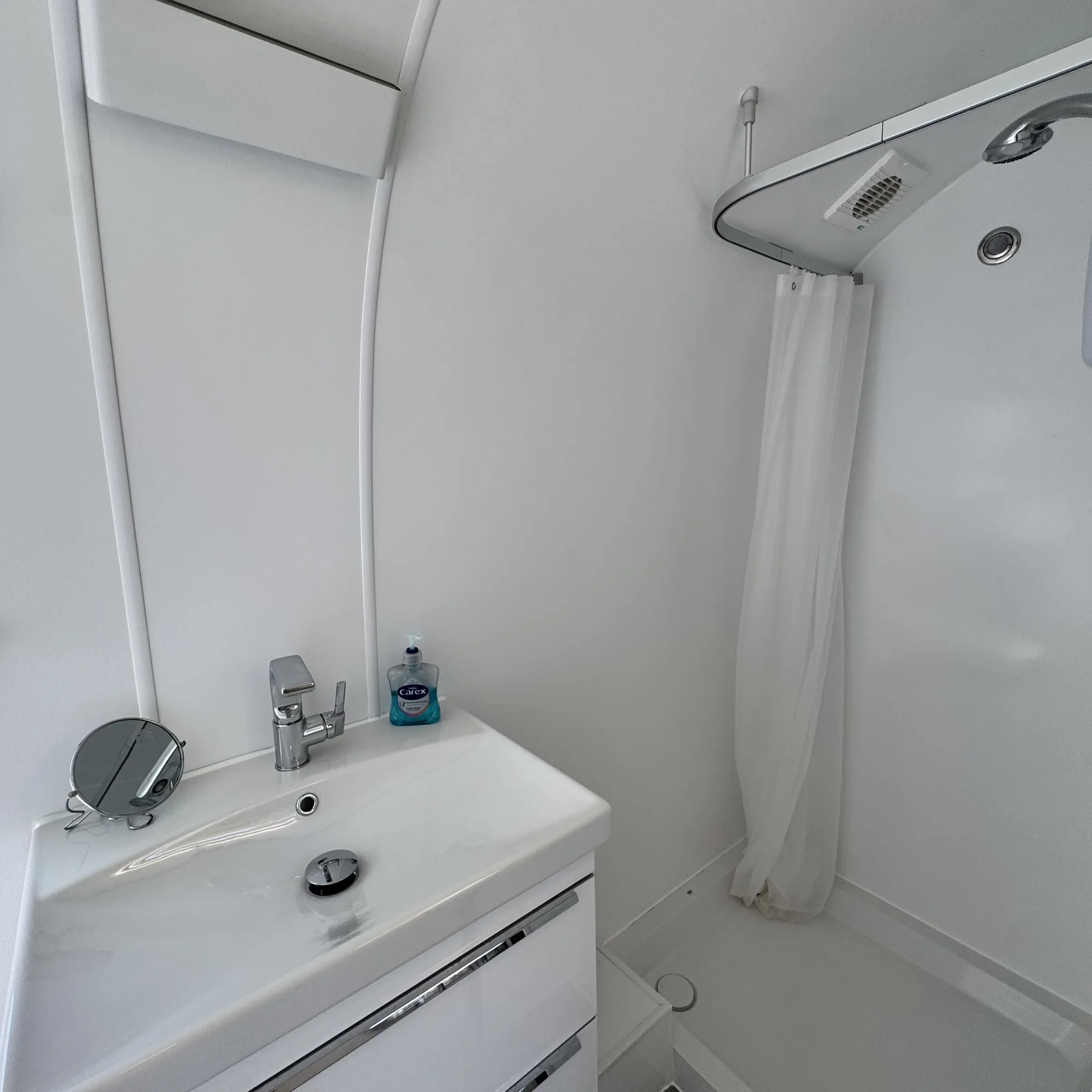 The compact bathroom inside the Airstream, with basin, mirror and shower