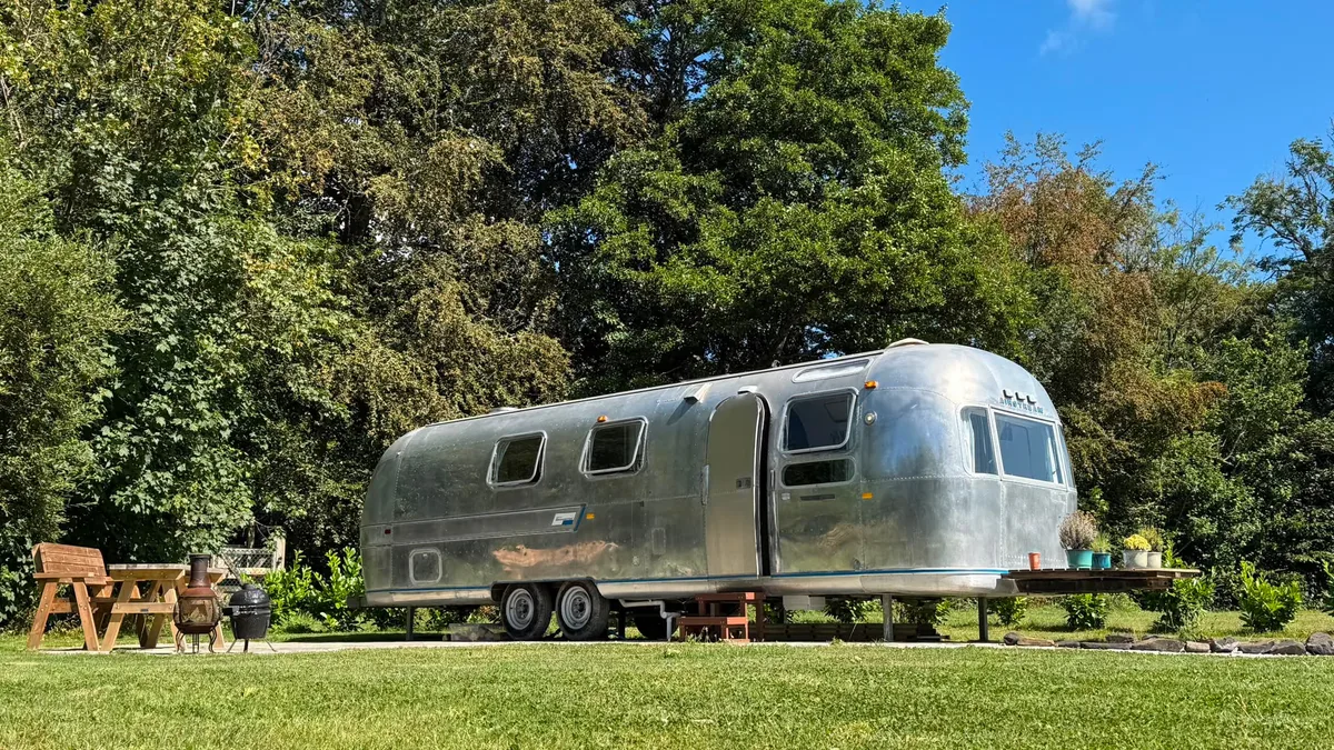 The polished aluminium Airstream at Boskenna, parked on its own pitch with a picnic bench and chiminea alongside