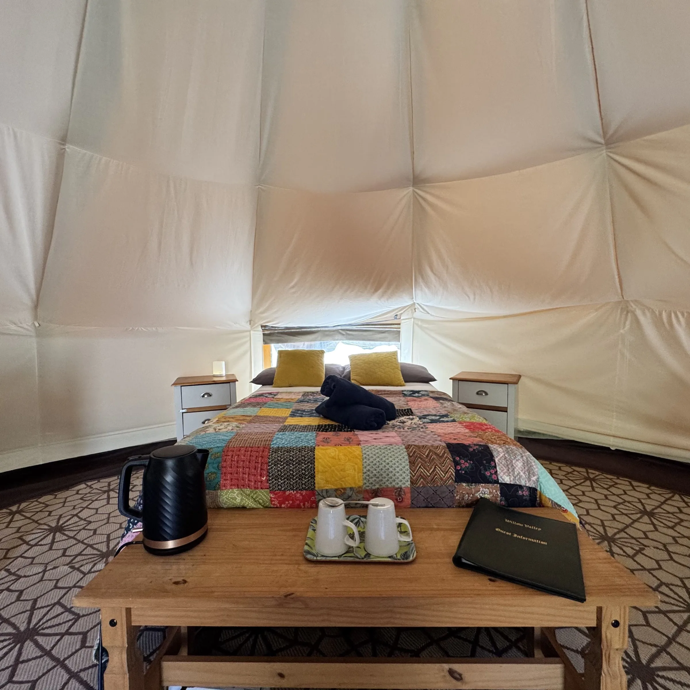 The double bed at Hartland, made up with a patchwork cushion and a low table set with a kettle alongside