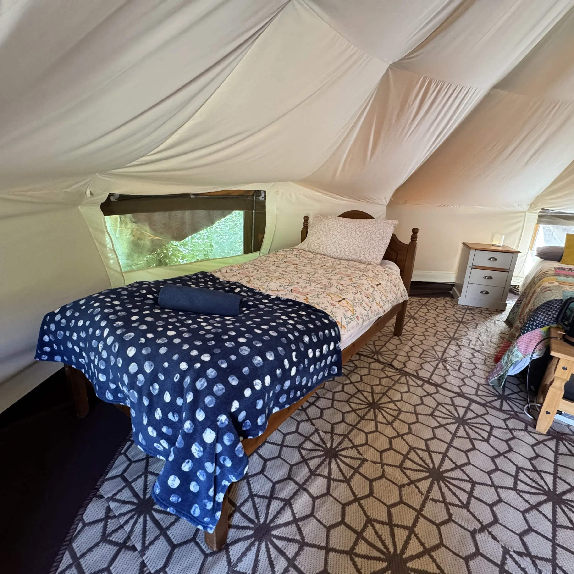 One of the single beds at Hartland, neatly made up beside the tent’s canvas wall