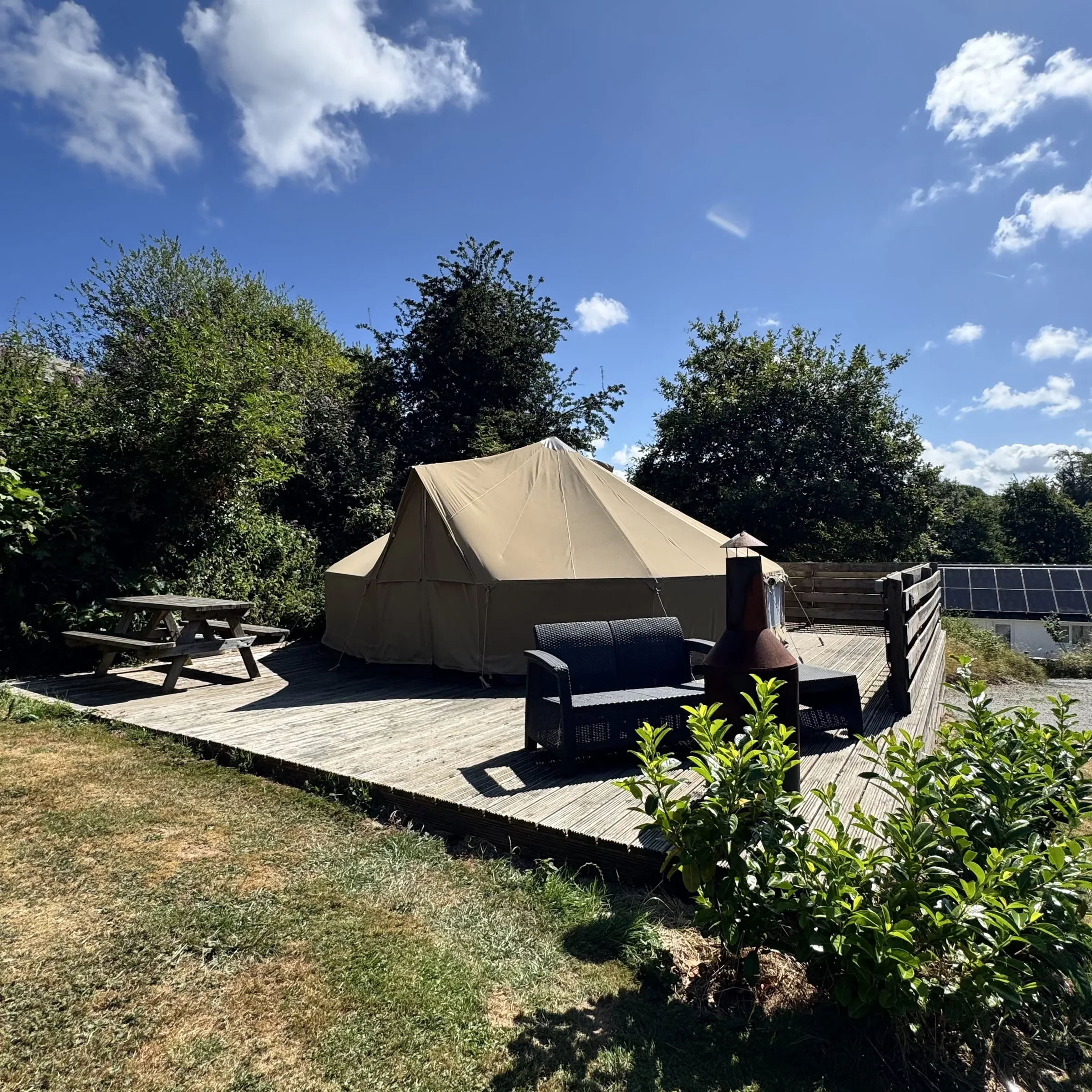Hartland’s bell tent on its timber deck, with the rattan sofa, chiminea and picnic bench out front