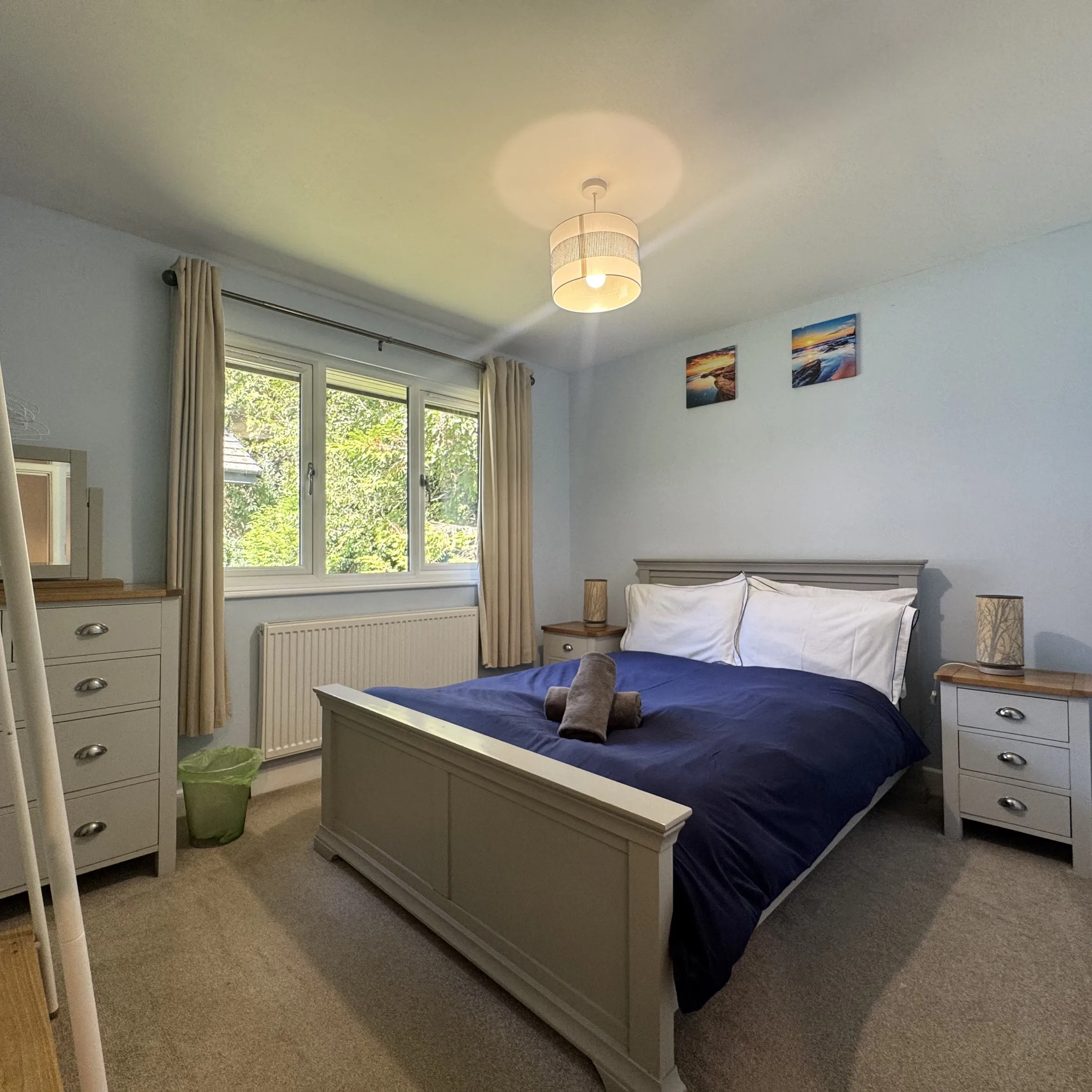 The double bedroom at Heath, made up in navy, with drawers and a window onto the garden