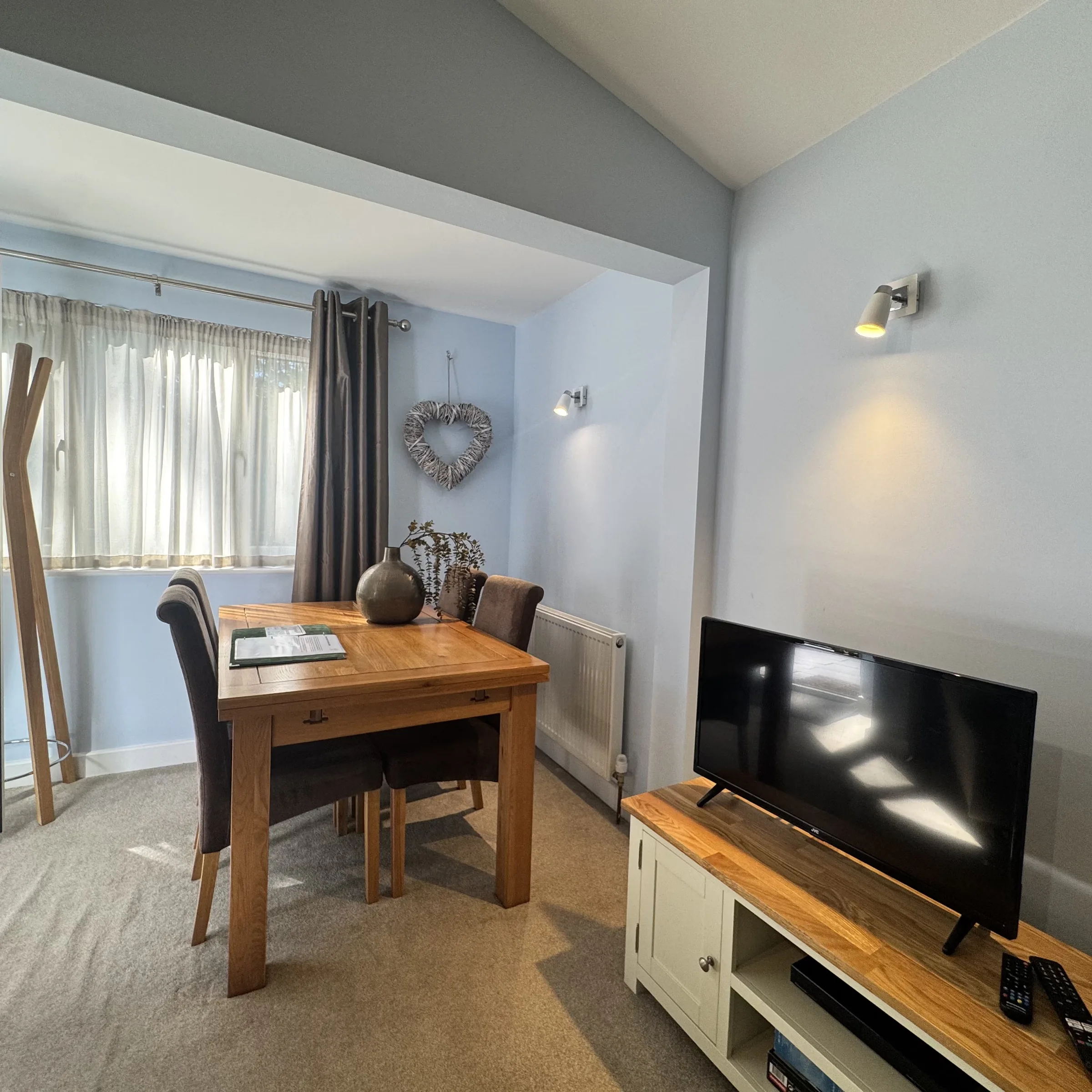 The dining table and living area in one of the lodges, set beside the window with the television alongside