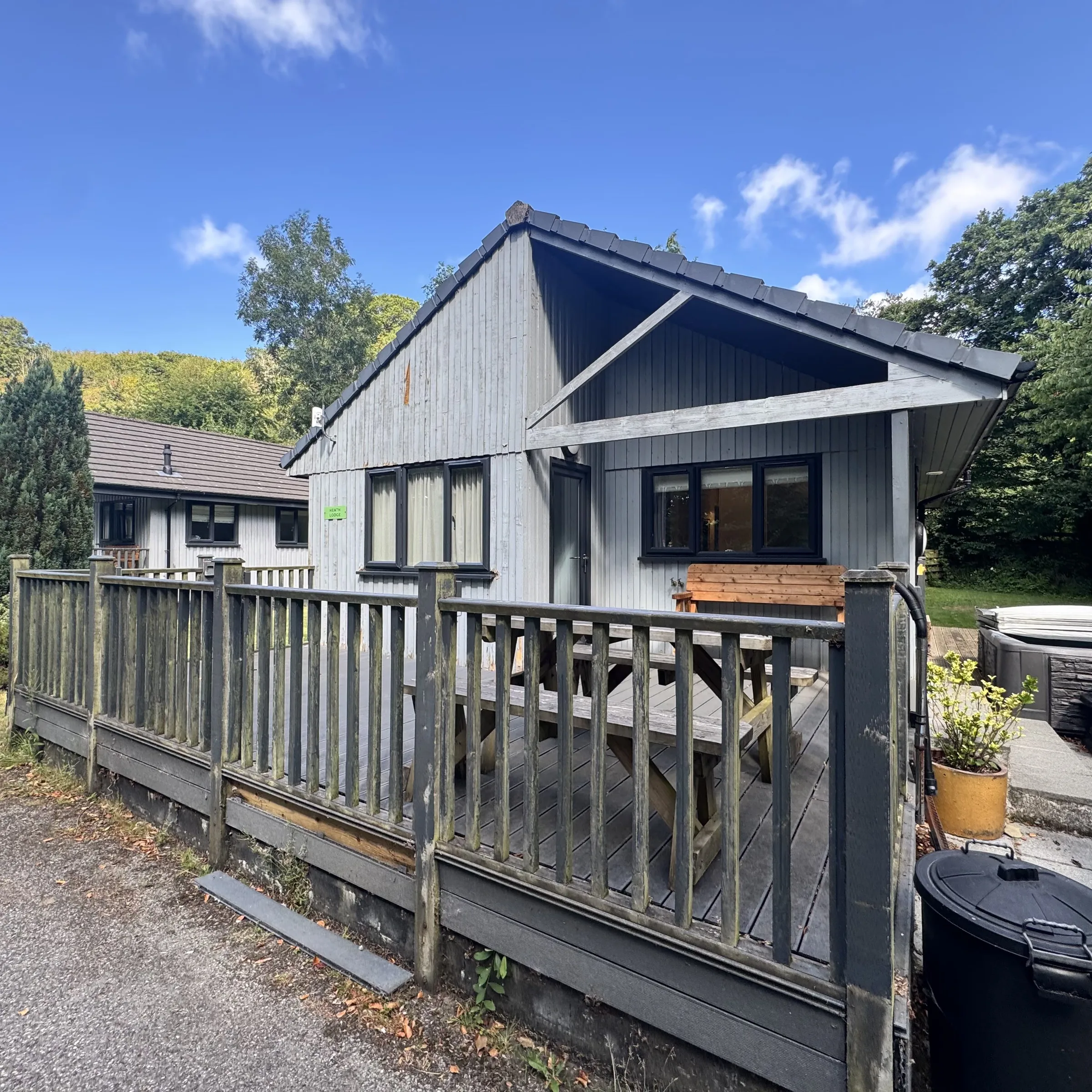 Heath lodge from the front, with its decked veranda, picnic bench and the hot tub alongside