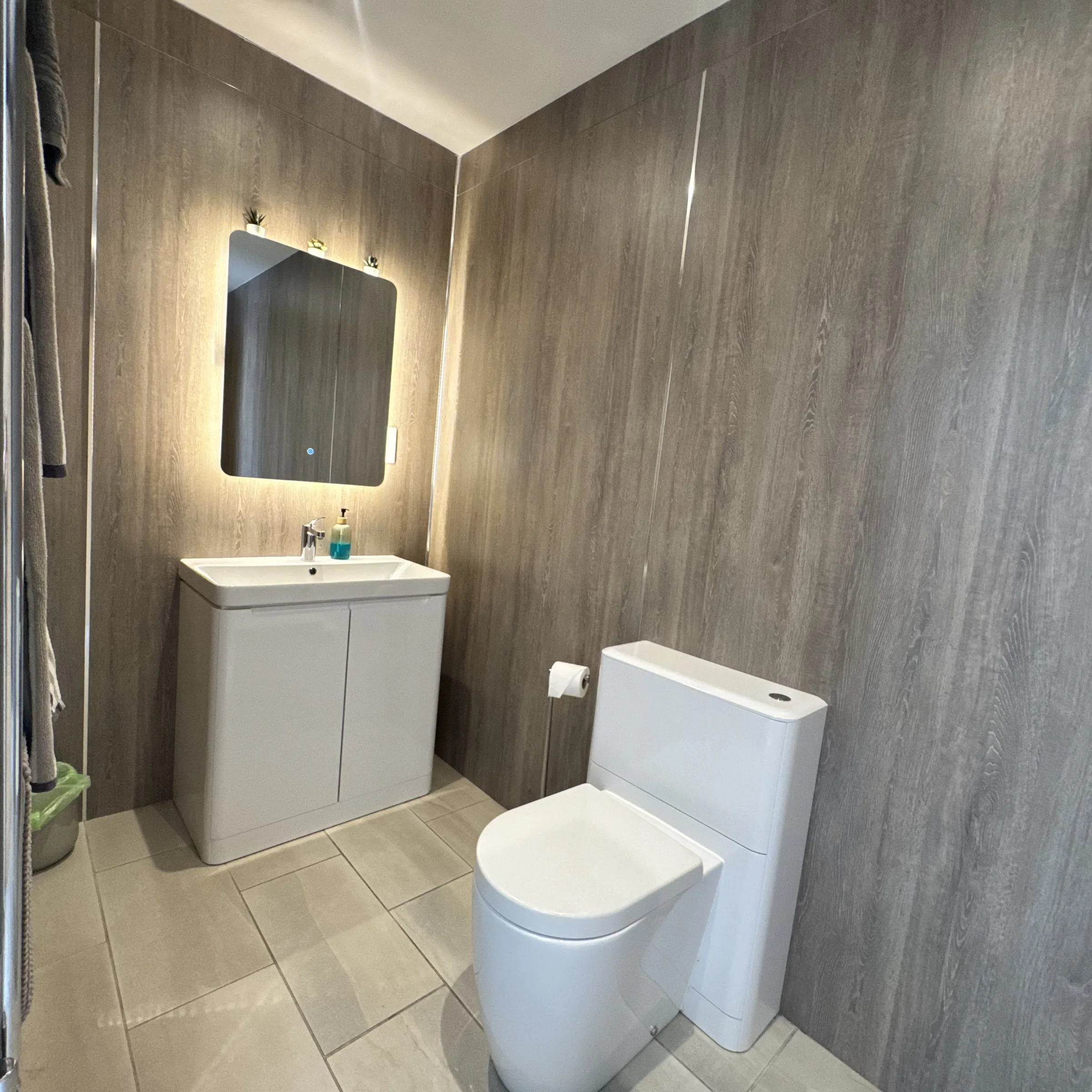 The basin, backlit mirror and WC in Helyk’s shower room