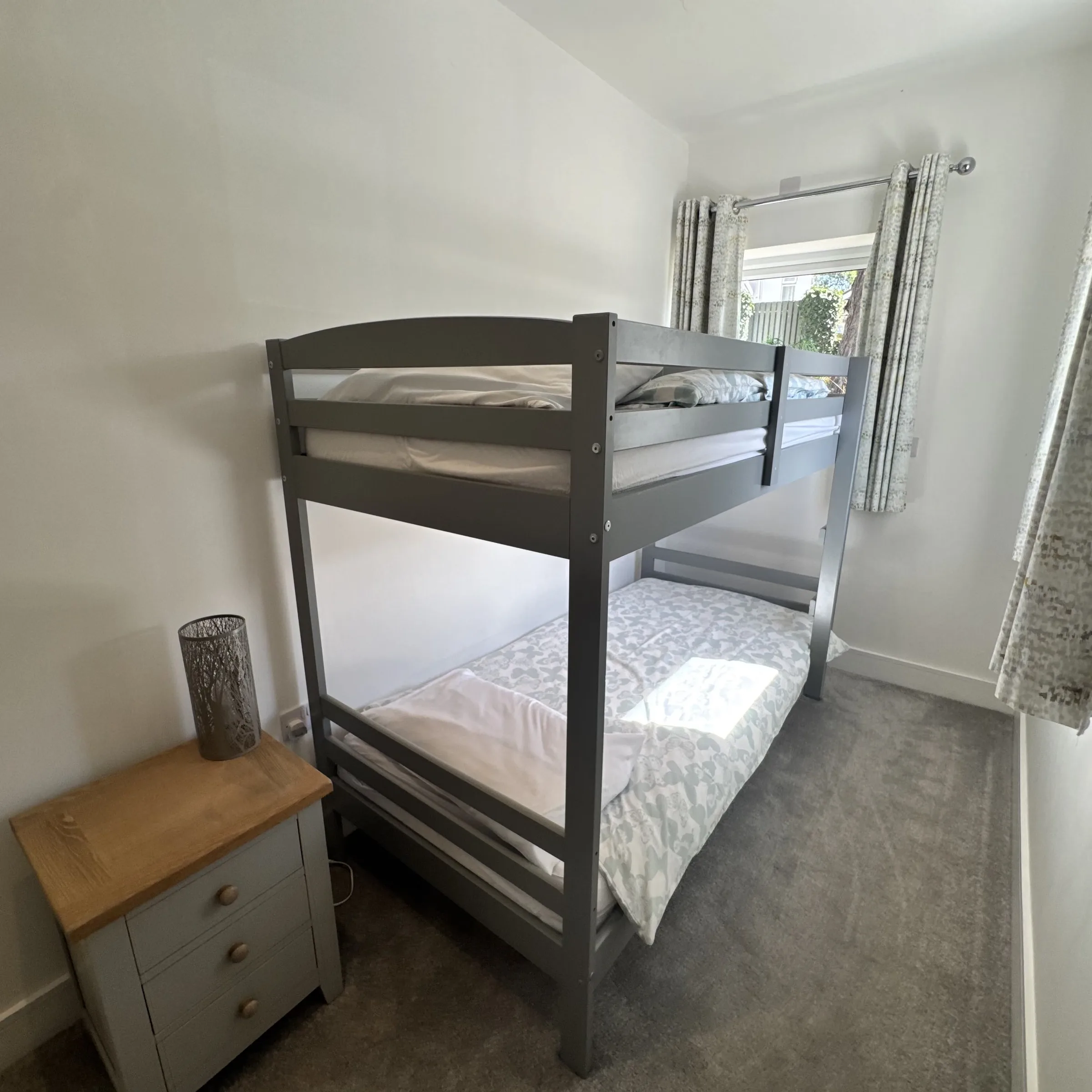 The bunk room at Helyk, made up with duvets, a bedside chest and lamp