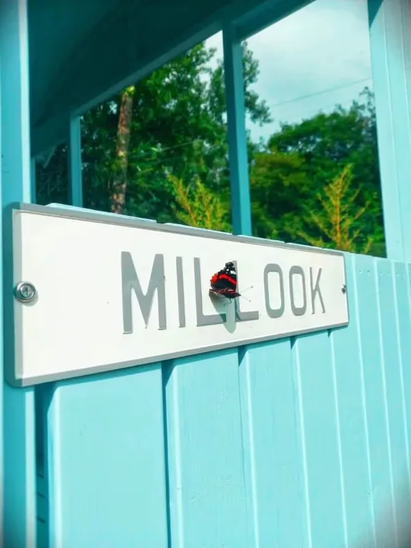 A red admiral butterfly resting on the enamel Millook nameplate beside the hut’s window