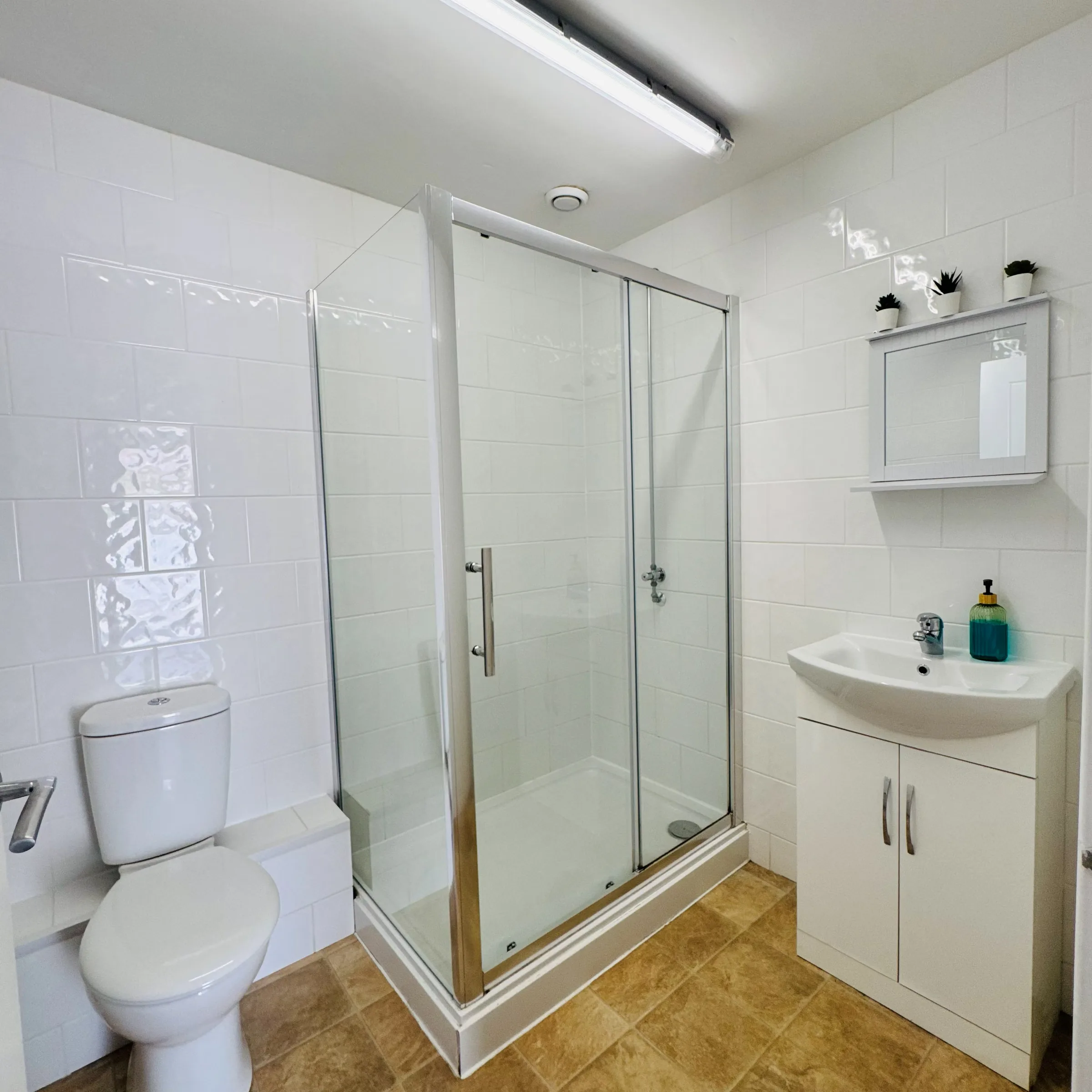 A second Mordros bathroom with a corner glass shower cubicle and tiled walls