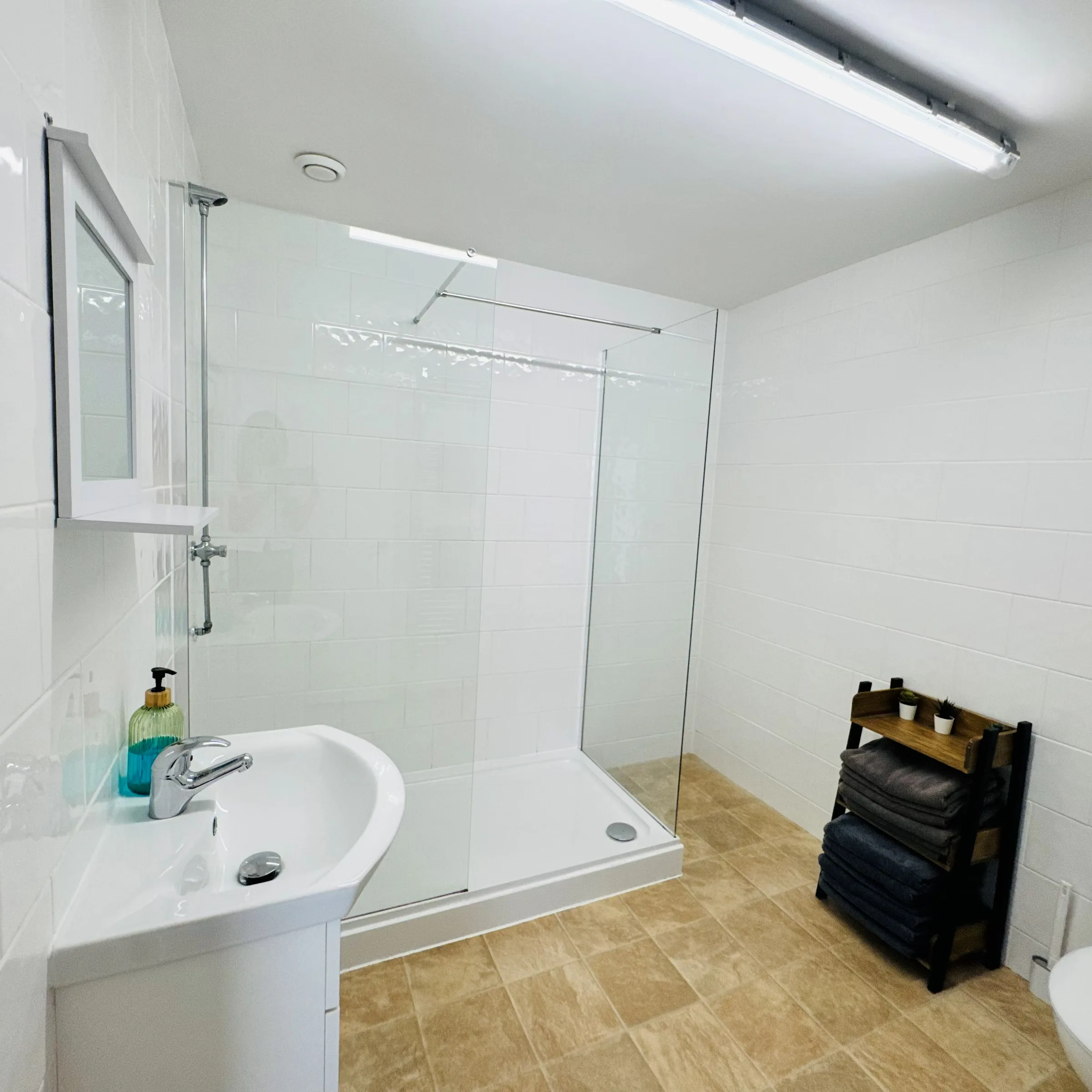 A third Mordros bathroom with a walk-in wetroom-style shower and a stack of towels alongside