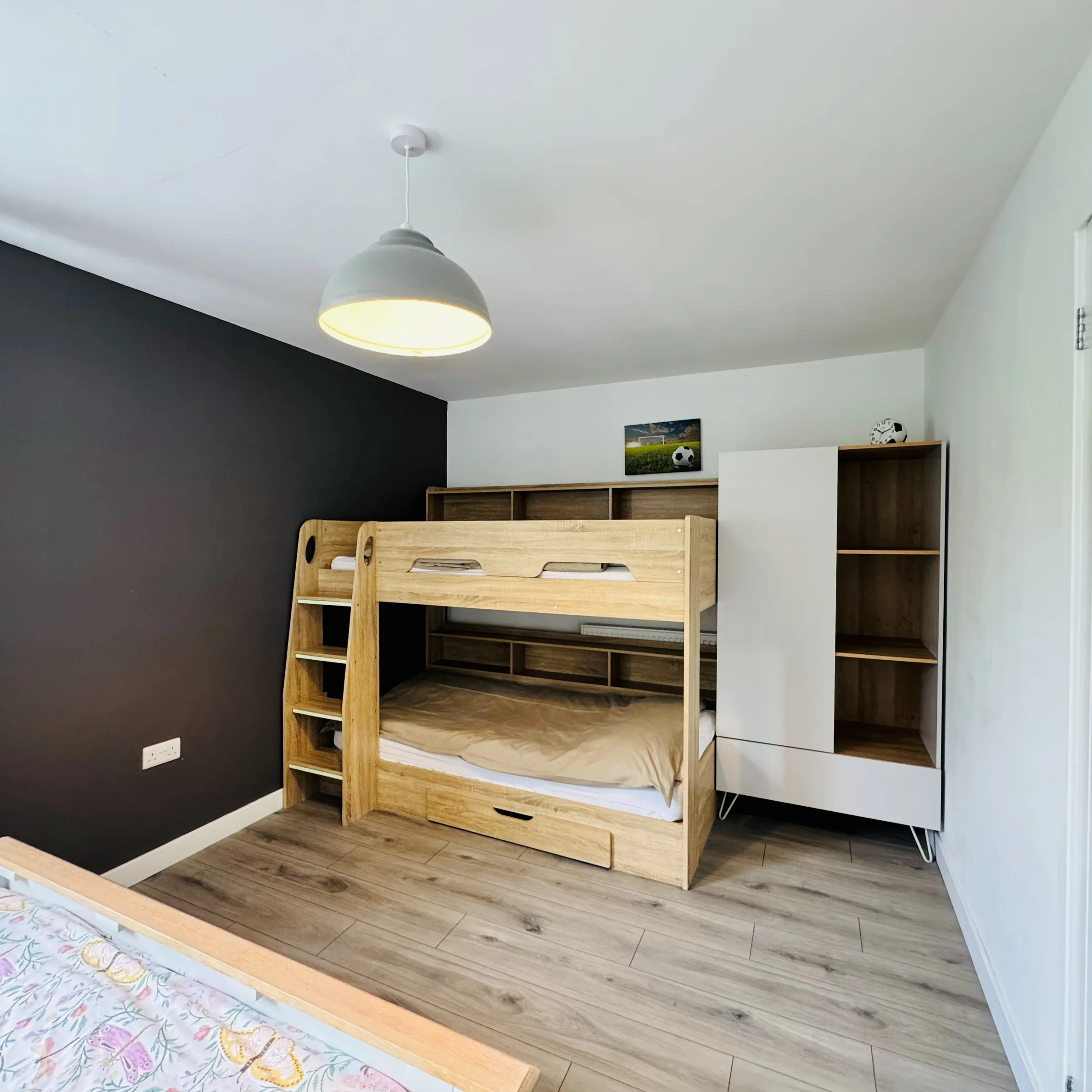 A second Mordros bedroom, a wooden bunk bed against a charcoal feature wall with a double bed alongside