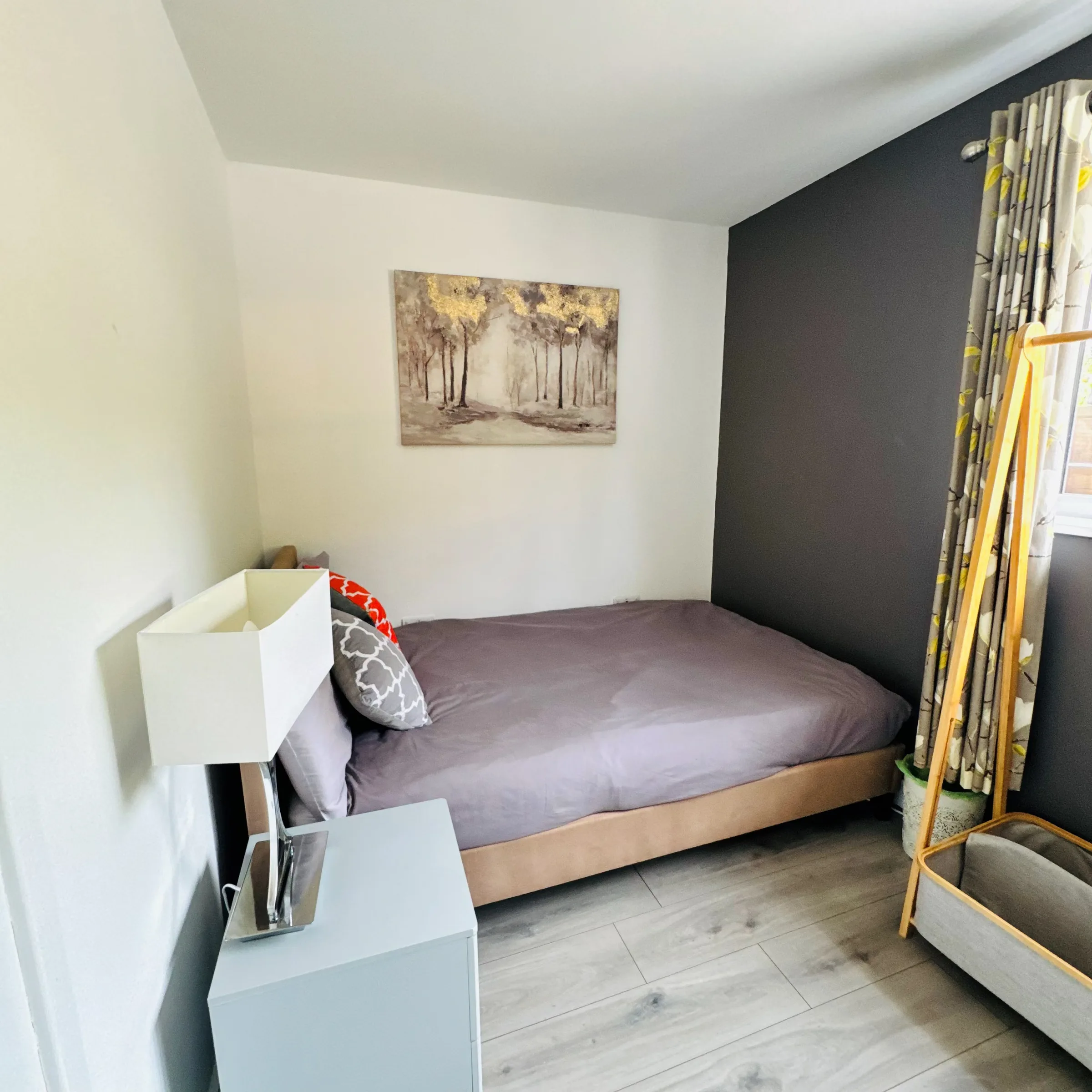 A Mordros bedroom in soft grey tones, with a woodland print above the headboard