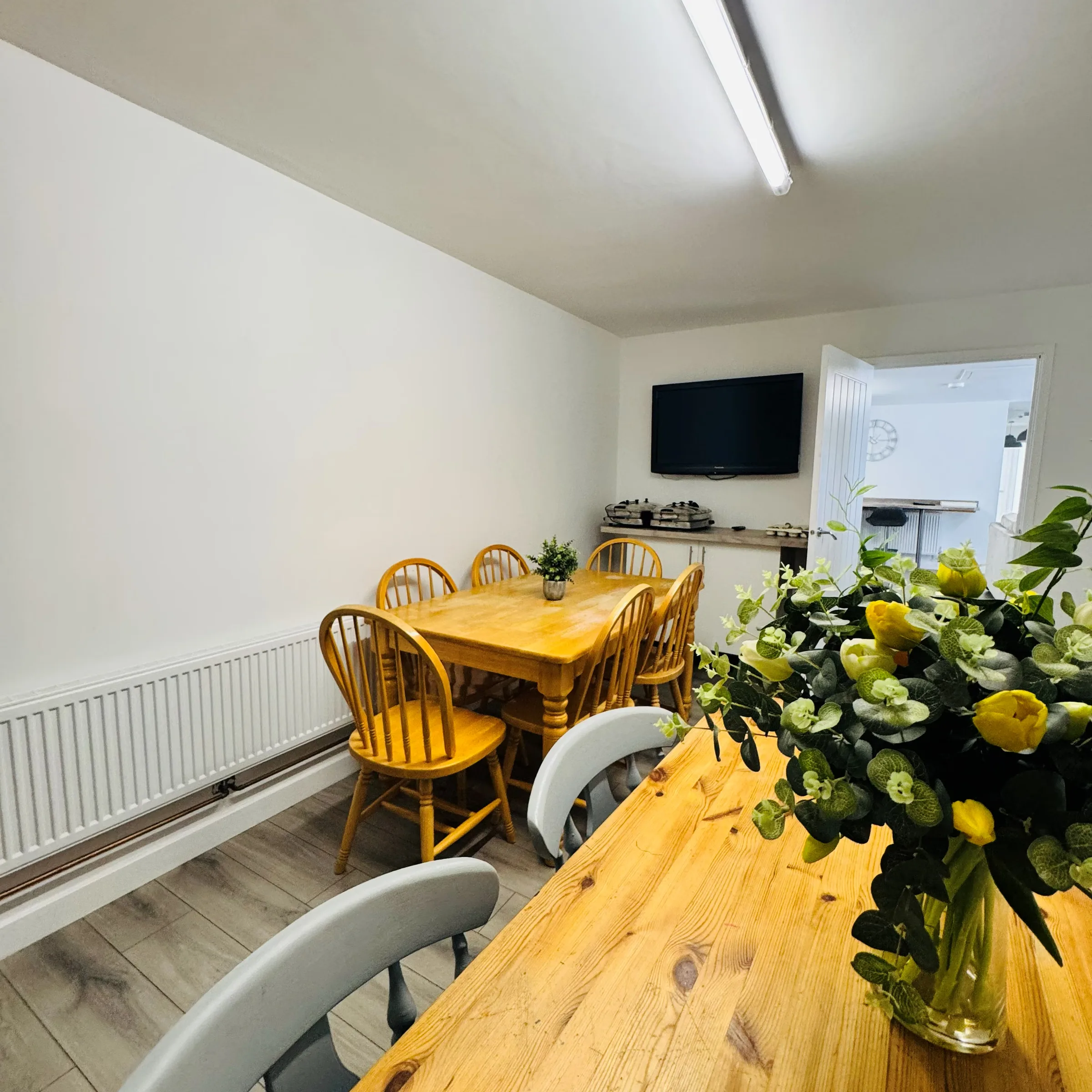 One of Mordros’s two dining tables, light oak with a jug of flowers, room enough for the whole group to sit down together