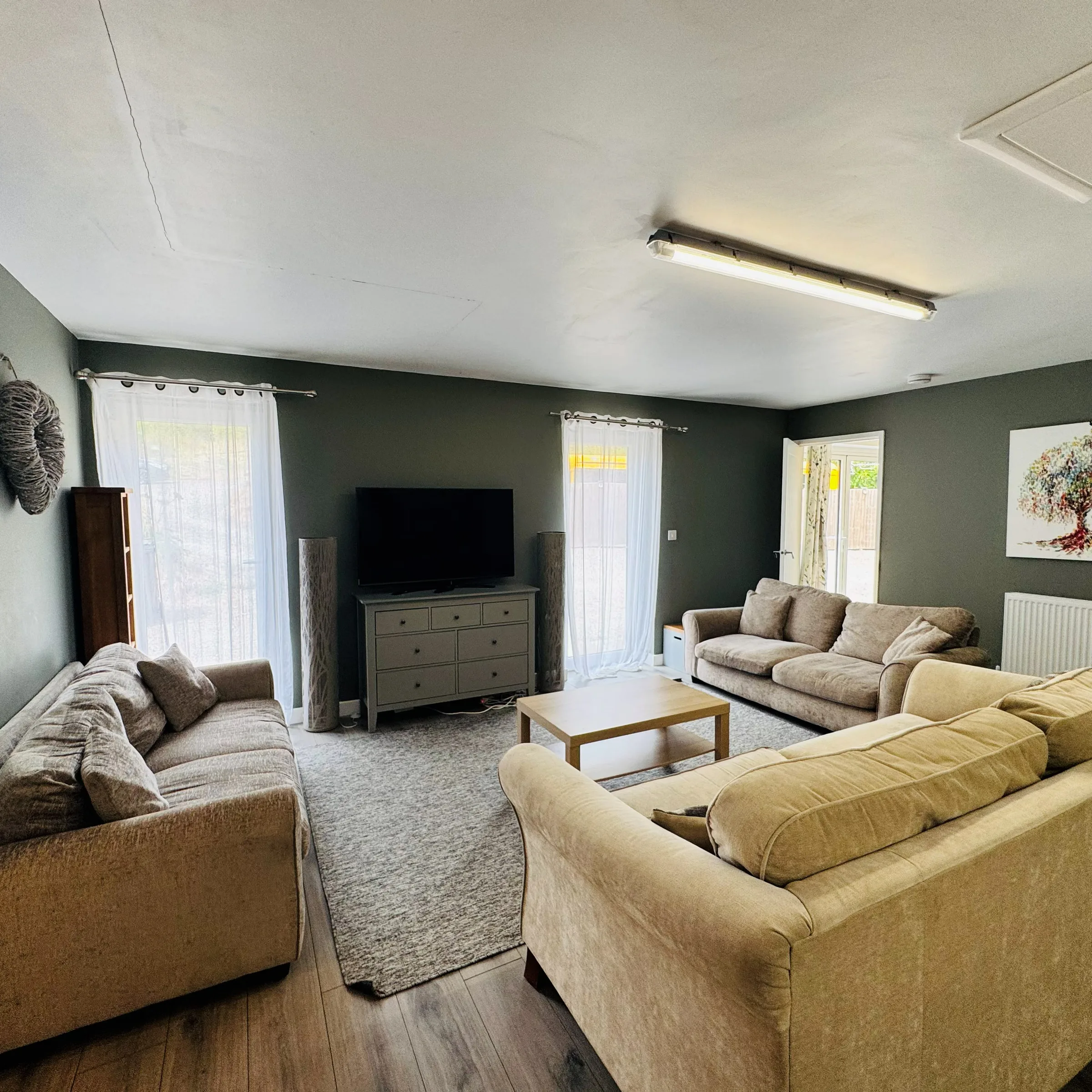 The lounge at Mordros, two large sofas around a coffee table against a charcoal feature wall, with a mounted television