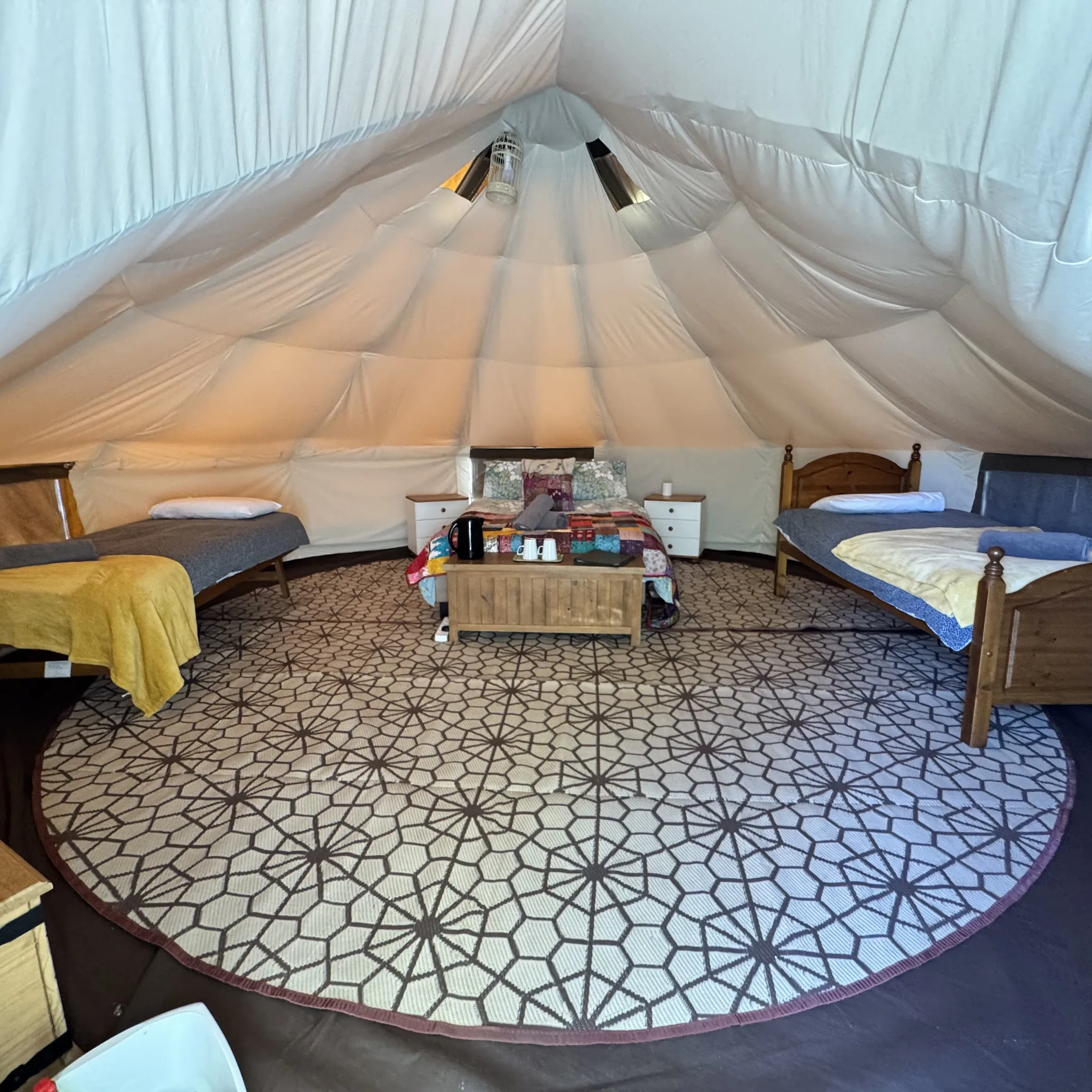 Inside one of our bell tents: the double bed and a single bed either side of the centre table, matting underfoot. Fistral is laid out the same way.