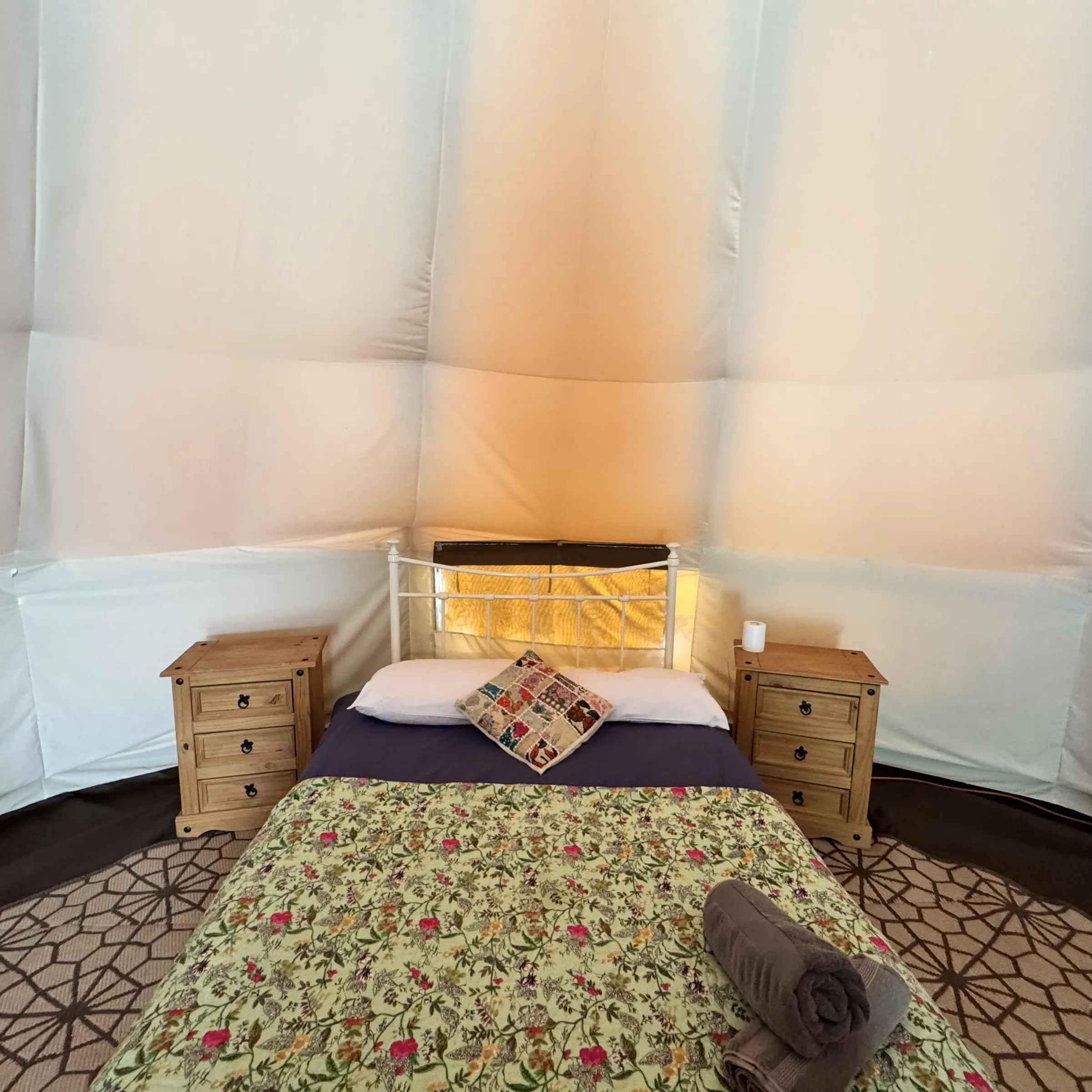 The double bed at St Enodoc, made up with a patchwork cushion and rolled towels