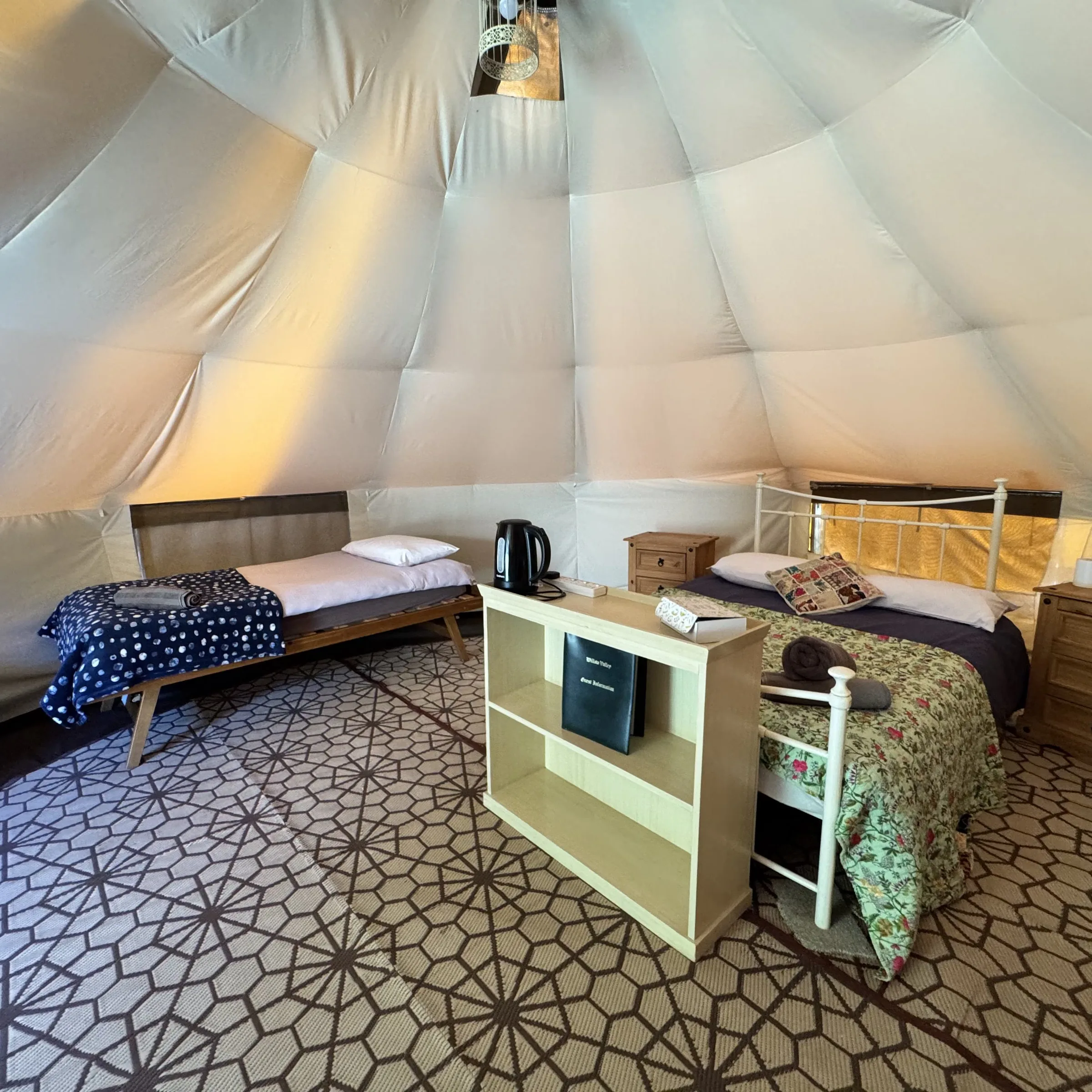 Inside one of our bell tents: the beds made up either side, with the kettle and the guest folder on the table between them. Fistral and Polzeath are laid out the same way.