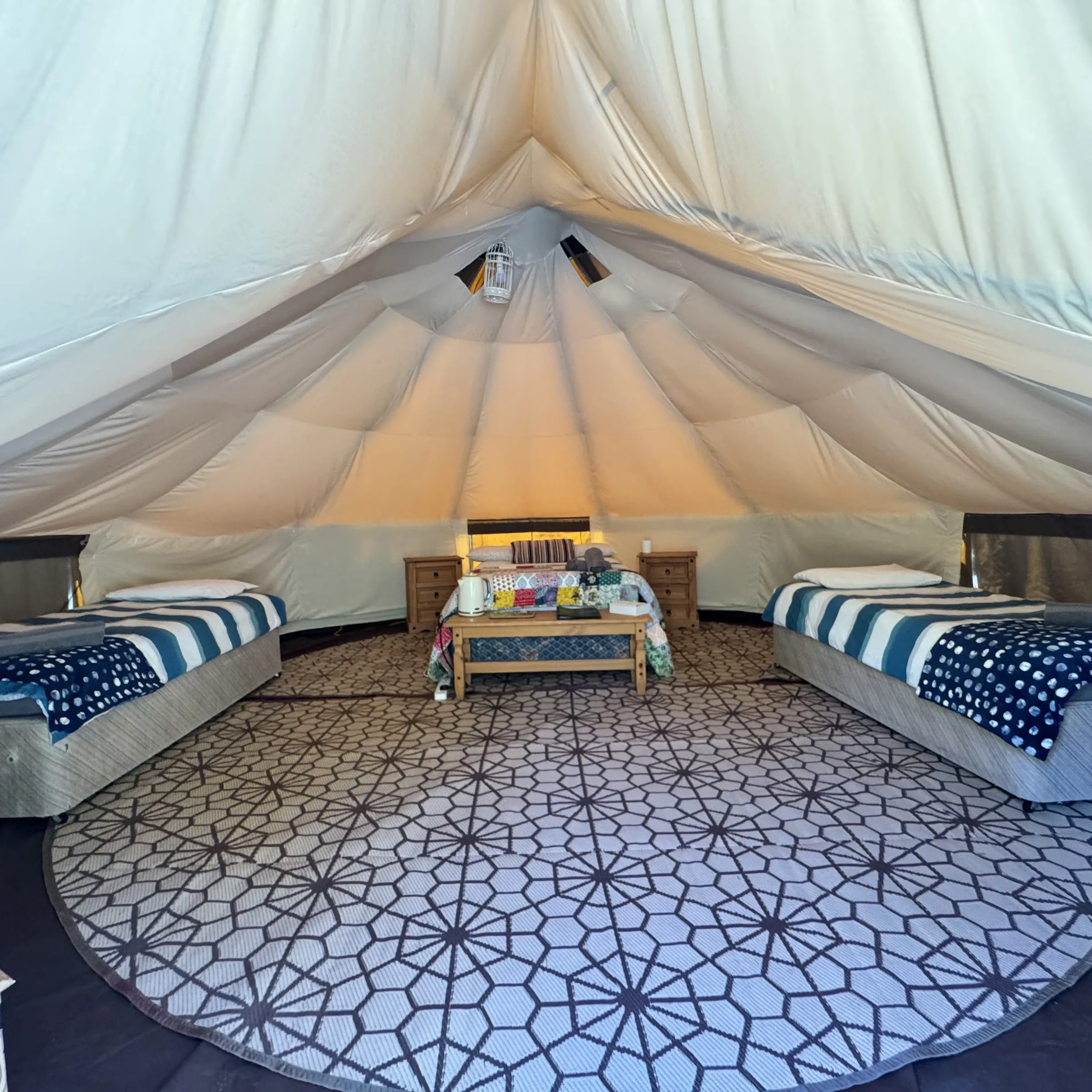 Inside one of our bell tents: two single beds either side and a centre table with the kettle and guest folder on it. Polzeath is laid out the same way.