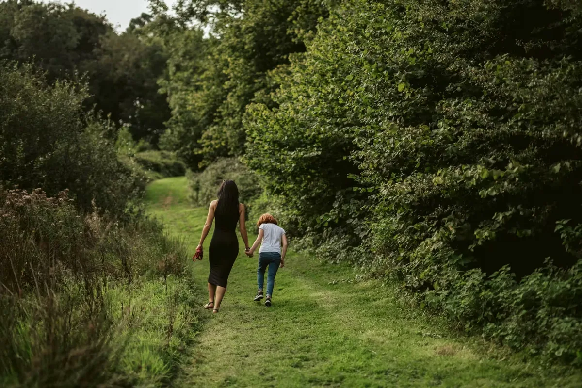 Two guests walking a mown grass path up through the trees on the valley side