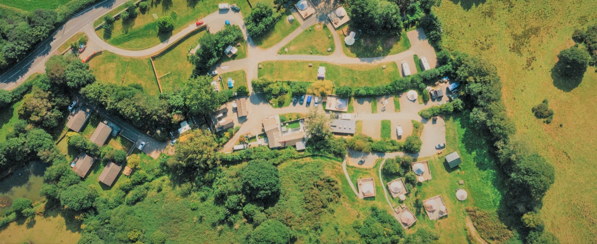 Willow Valley from directly overhead: the gravel drives and pitches, the lodges among the trees and the bell tent decks along the valley side